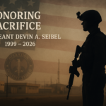 alt_text: A soldier stands solemnly before a memorial with a Texas flag, honoring a fallen comrade.